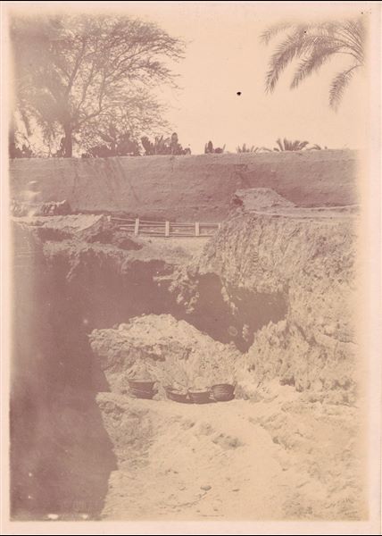 Trincea di scavo nell’area del santuario del sole. Sullo sfondo si trova il muro della casa di Latif. Fotografia sovraesposta e realizzata a seppia. Scavi Schiaparelli.