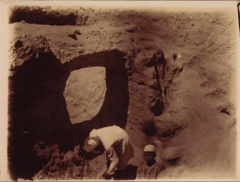 Trincea di scavo nell’area del Kom, dove emerge una struttura a ponte. I tre giovani operai risultano sfocati, probabilmente perché in movimento. Scavi Schiaparelli.