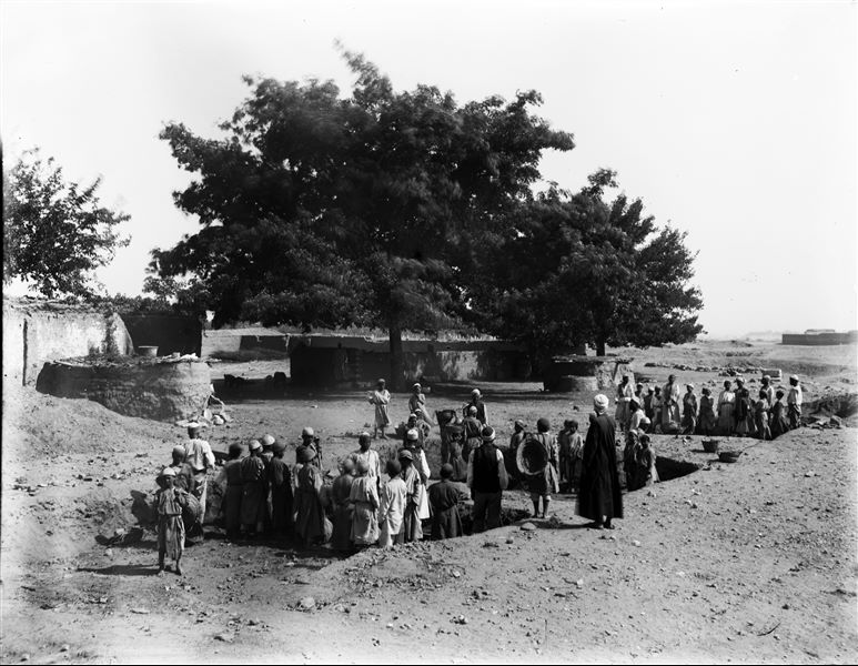 Excavations in the Bey field in the kom area, near a saqiyah. Some houses are visible in the background, probably from kom. Schiaparelli excavations.