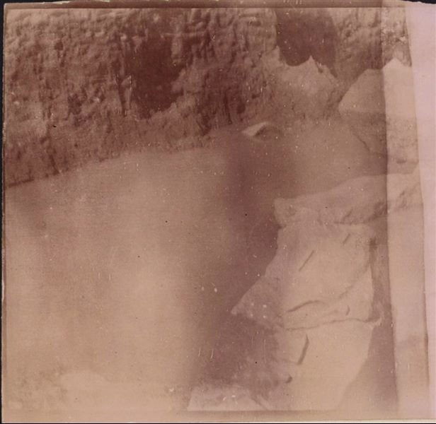 Tempio di Mnevis, trincea con frammenti del naos di Psammetico. Da notare il terreno fangoso. La stampa su carta è stata virata con il color seppia. Scavi Schiaparelli.