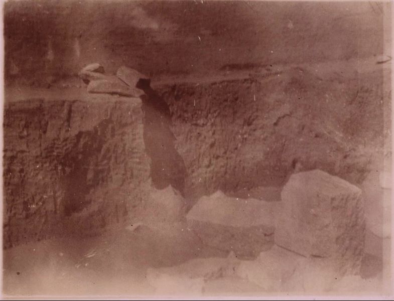 Temple of Mnevis, trench with fragments of the naos of Psamtik I. Note the muddy ground. This paper print has been toned with sepia.  Schiaparelli excavations. 