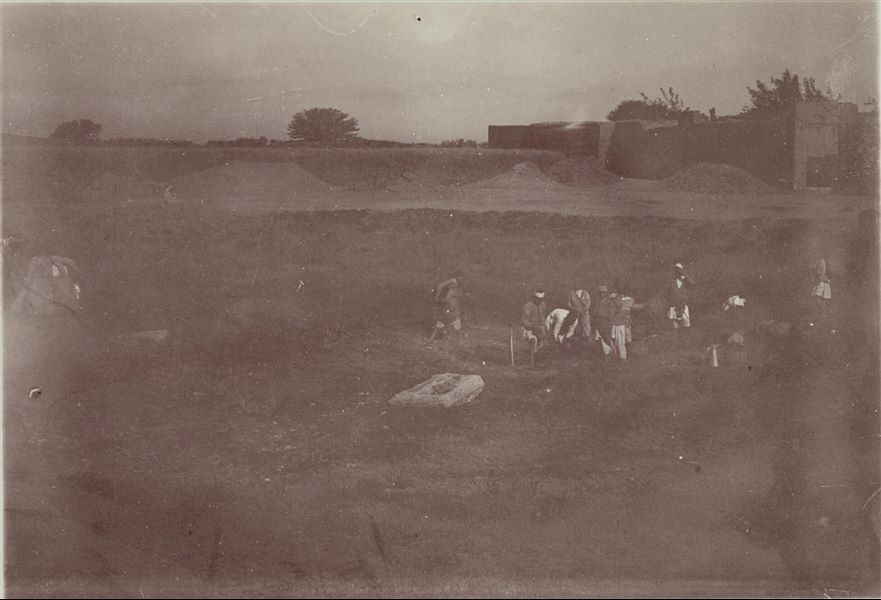 Temple of Mnevis, trench with fragments of the naos of Psamtik I. Note the muddy ground. This image is not entirely clear, due to the shot not being captured perfectly, as well as the worn condition of the paper on which the image was printed. Schiaparelli excavations.