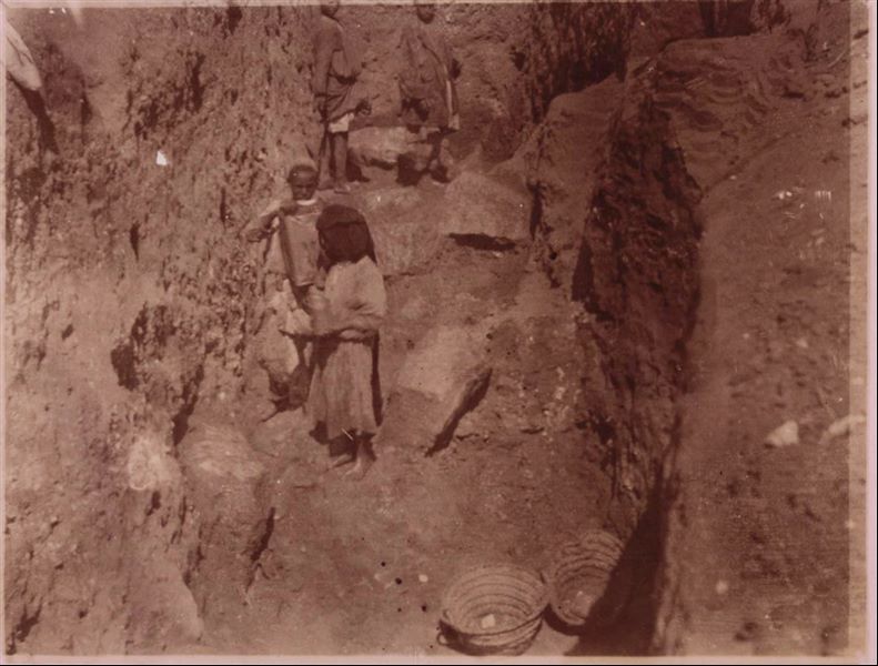 Tempio di Mnevis, trincea con frammenti del naos di Psammetico. Da notare il terreno fangoso. La stampa su carta è stata virata con il color seppia. Scavi Schiaparelli.