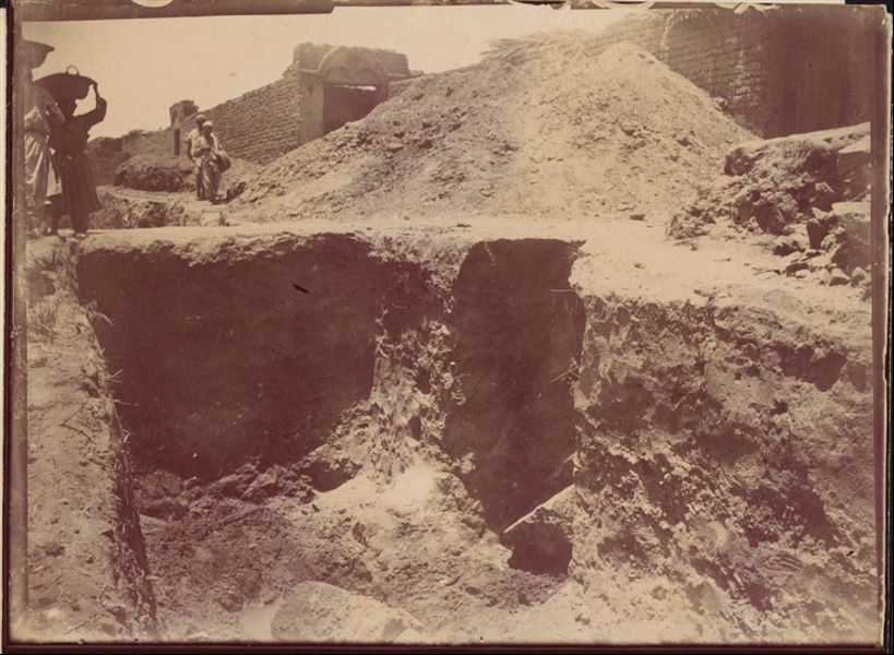 Tempio di Mnevis, trincea con frammenti del naos di Psammetico. Da notare il terreno fangoso. La stampa su carta è stata virata con il color seppia. Scavi Schiaparelli.