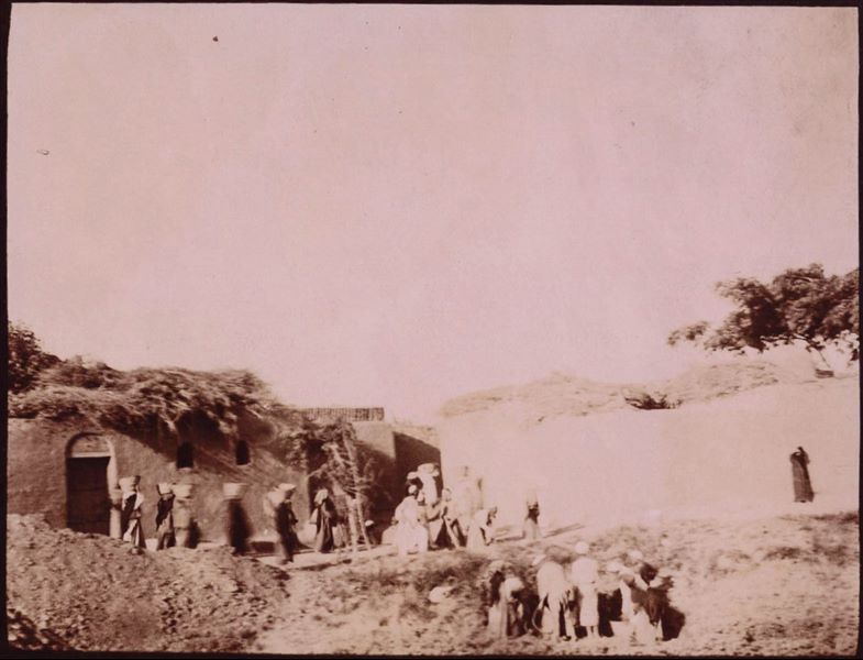Temple of Mnevis, trench with fragments of the naos of Psamtik I, close to housing. This paper print has been toned with sepia.  Schiaparelli excavations.