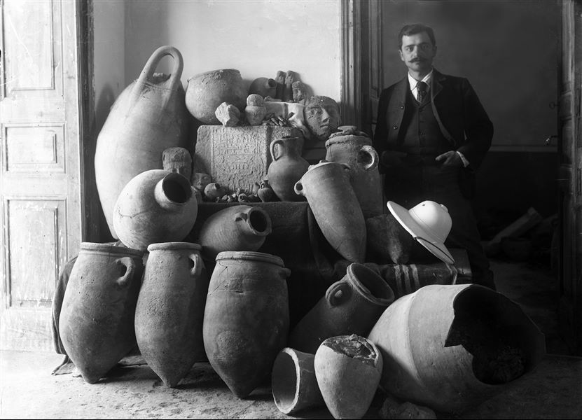Vases found during the archaeological excavations of 1903. The features of the surrounding environment suggest that it is a building in Egypt, however a room inside the Turin Museum should not be ruled out. To corroborate the hypothesis that the photo was taken in Egypt, here represented is Evaristo Breccia; classical archaeologist and future director of the Greaco-Roman Museum of Alexandria, who in February 1903 opened the site for the mission in Giza. 