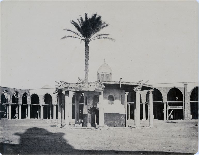 Cortile della moschea di ‘Amr, la moschea più antica del Cairo, costruita nel VII secolo d.C. dal califfo Omar in onore del generale delle truppe islamiche, ‘Amr Ibn al-’As, che aveva invaso e conquistato il Paese alcuni anni prima. Nulla, tuttavia, rimane della struttura originaria, a causa delle modifiche e dei rifacimenti dei secoli successivi.  Nell’immagine ottocentesca si nota il colonnato arcato, tutt’ora esistente, mentre la struttura centrale ha subito nel tempo alcune modifiche. La firma dell’autore si trova in basso a sinistra.