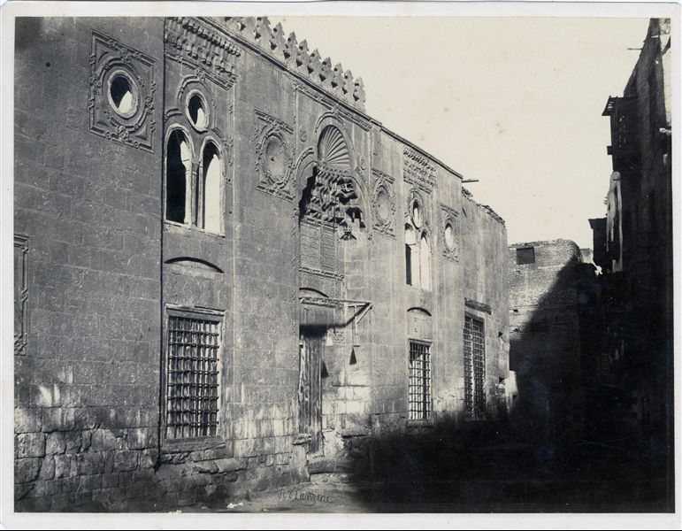 Particolare di una via della città del Cairo, nel quale sono visibili alcune elaborate decorazioni architettoniche sulle facciate delle abitazioni, tipiche dell’arte musulmana. La firma dell’autore si trova in basso.