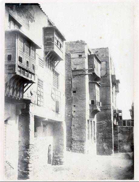Detail of a street in the city of Cairo where some mashrabiyas (characteristic balconies with elaborate wooden grates) are visible. The author's signature can be found at the bottom left.  