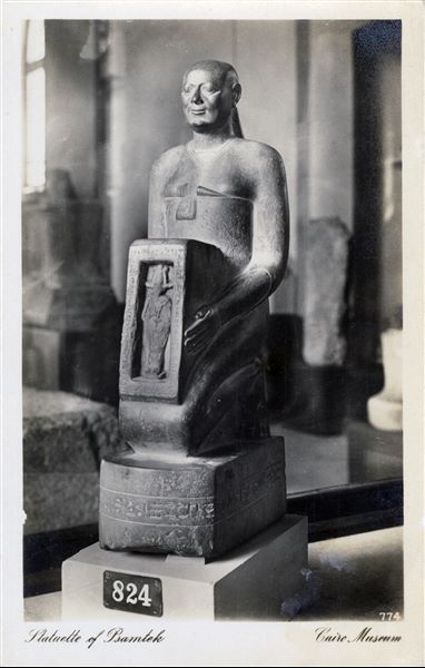 Sala del Museo Egizio del Cairo. Statua di Psammetico, capo degli atelier degli orafi reali, trovata nell’area di Menfi. XXVI dinastia. Album “Cartes postales”. 