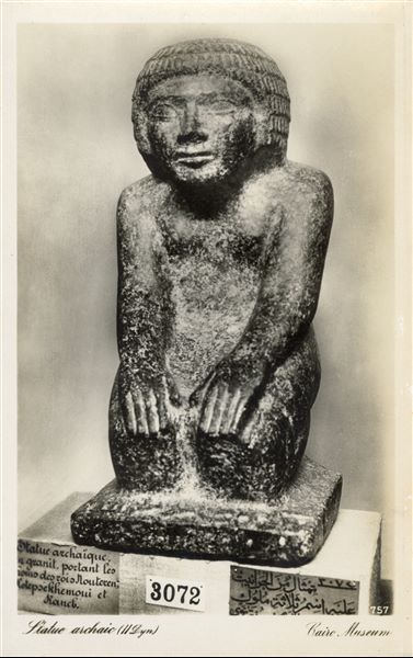Gallery in the Egyptian Museum in Cairo. Statue of an official from the Early Dynastic Period. On its shoulder there are the names of three kings from the 2nd dynasty: Hotepsekhemwy, Raneb (or Nebra), Nynetjer. Album “Cartes postales” (Postcards).