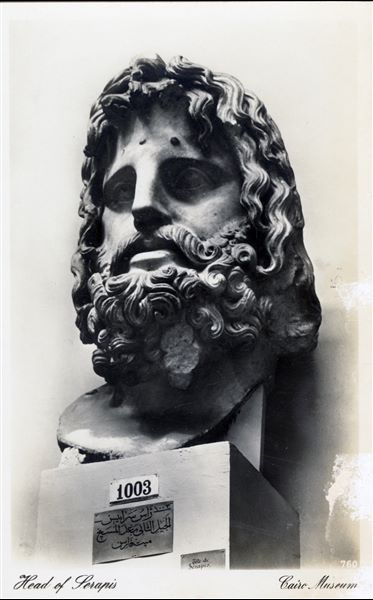 Sala del Museo Egizio del Cairo. Testa del dio Giove-Serapide, del II a.C., in marmo bianco. Trovata a Mit Faris. Album “Cartes postales”. 