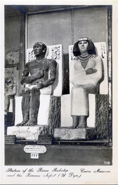 Gallery in the Egyptian Museum in Cairo. Statues of Prince Rahotep (Cairo CG 3), and Princess Nofret (Cairo CG 4). Rahotep was supposedly the son of the 4th dynasty pharaoh Snefru and half-brother of Cheops (Khufu). Their mastaba tomb was discovered at Meidum. Album “Cartes postales” (Postcards).