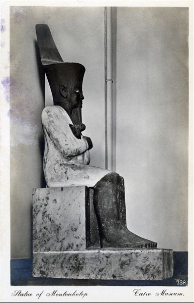 Gallery in the Egyptian Museum in Cairo. Painted Osiride sandstone statue of Pharaoh Montuhotep II (11th dynasty), the ruler who reunified Egypt, thus inaugurating the Middle Kingdom, at the beginning of the second millennium BCE (Cairo JE 36195). Album “Cartes postales” (Postcards).