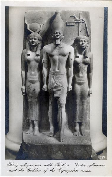 Gallery in the Egyptian Museum in Cairo. Triad consisting of the pharaoh Menkaure in the centre, flanked by the goddess Hathor and the goddess of the 17th nome of Upper Egypt. Album “Cartes postales” (Postcards).