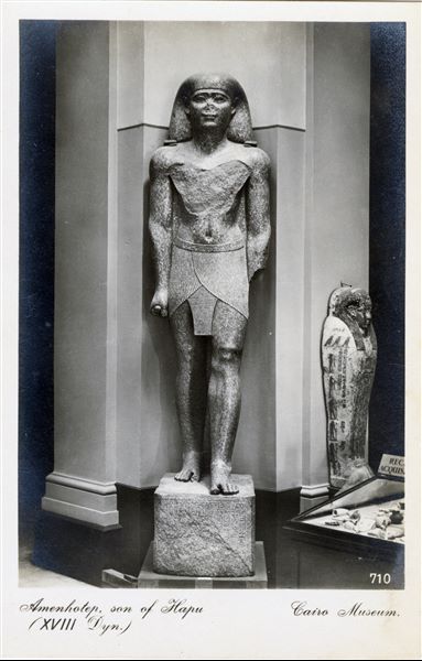 Gallery in the Egyptian Museum in Cairo. Statue of the public official Amenhotep, son of Hapu. 18th dynasty. Album “Cartes postales” (Postcards).