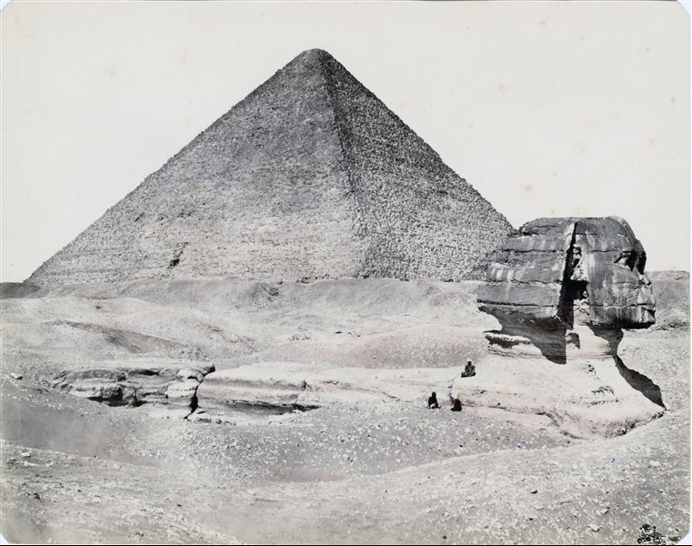 La fotografia mostra una parziale veduta della piana di Giza, con il profilo della Sfinge, non ancora liberata dalle sabbie, e la piramide del faraone Cheope.