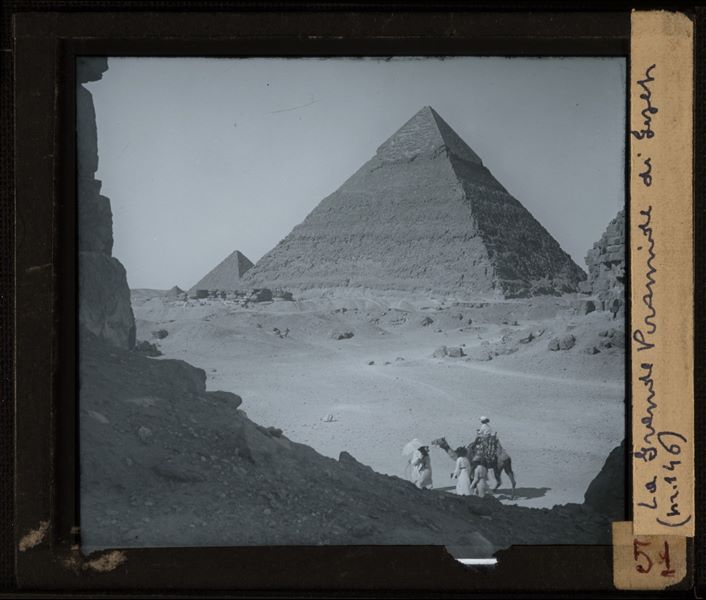 Gruppo di turisti con cammello davanti alle piramidi di Giza. É probabile che si tratti di una foto ottocentesca.