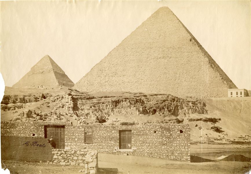 The pyramids of the pharaohs Khafre and Khufu overlook the Giza Plateau, where there are some modern buildings. The author's signature is visible at the bottom left.