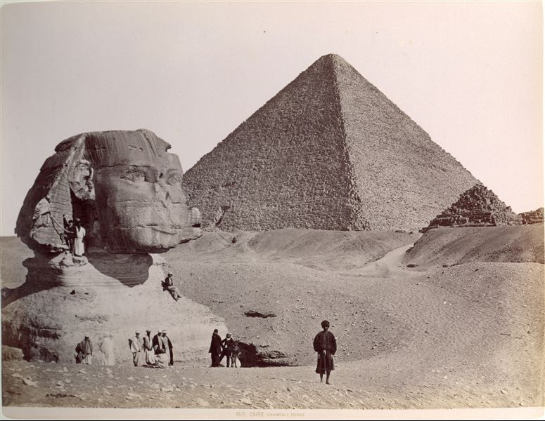 Veduta della Sfinge, parzialmente liberata dalle sabbie. Dietro di lei, si erge la piramide del faraone Cheope, la più grande della piana di Giza.