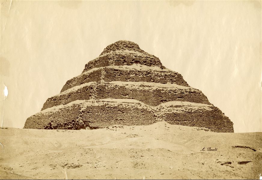 Fotografia della piramide a gradoni di Djoser, primo faraone della III Dinastia, a Saqqara. Tutt'intorno, l'area deve ancora essere scavata. In basso a destra è visibile la firma dell’autore.