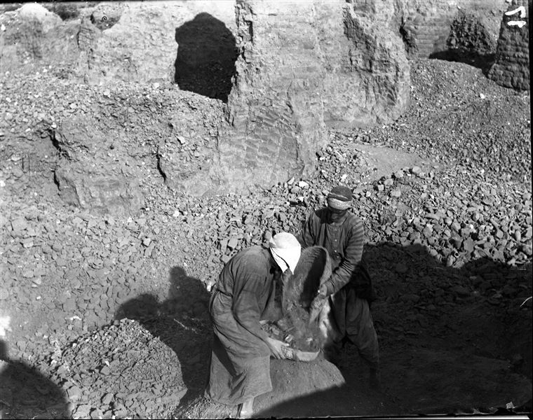 Excavating on the site, two workers are sifting dirt. The structure visible is unidentifiable. Schiaparelli excavations.