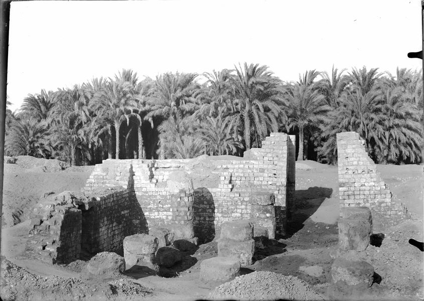 View from the area behind the remains of the temple of Amun (and Thoth) within the sacred enclosure of the sanctuary of Thoth. Remains of the columns in the inner courtyard can be seen. Schiaparelli excavations.