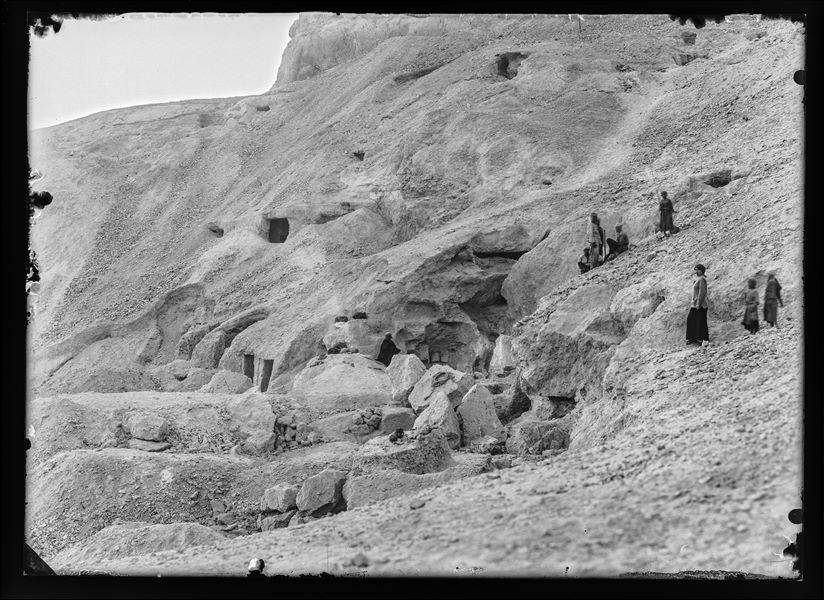 Scavi presso la necropoli rupestre di Assiut: oltre a diversi operai egiziani, che guardano verso l’obiettivo, si riconoscono alcuni accessi alle tombe. Scavi Schiaparelli. 