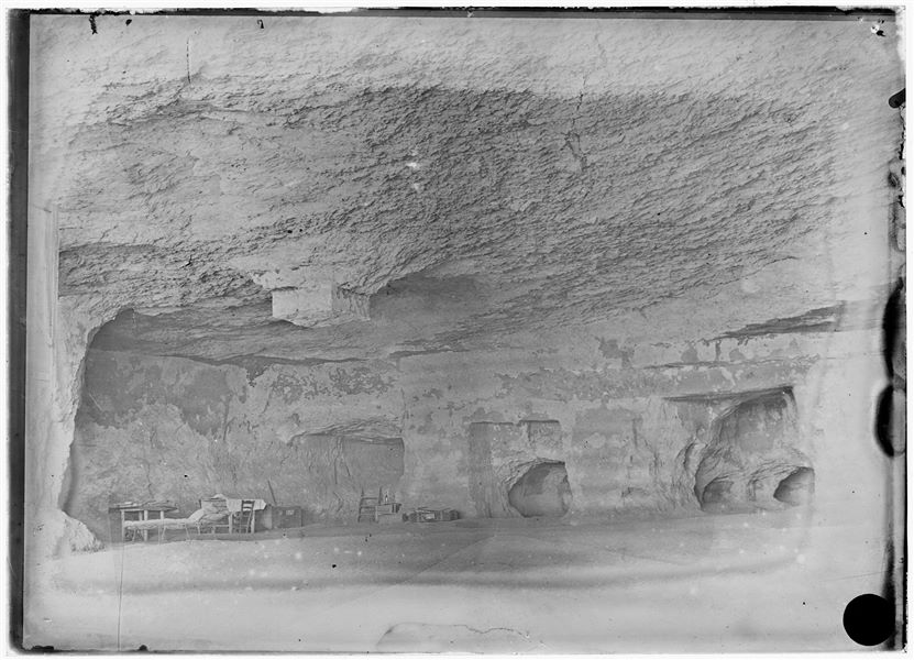 Veduta interna di una delle grandiose tombe di Assiut (tomba III), trasformata in sede operativa della missione. In alto sono visibili i resti di un pilastro quadrato ricavato direttamente dalla roccia. Scavi Schiaparelli.