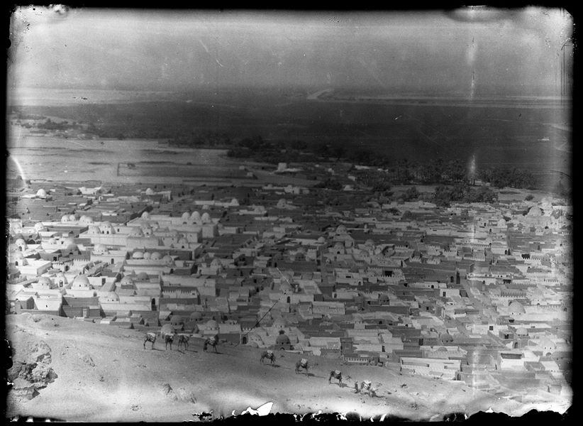 Il cimitero moderno di Assiut vista dall'alto. In primo piano una fila di cammelli guidati da un egiziano, mentre in fondo si riconosce il fiume Nilo. Scavi Schiaparelli.