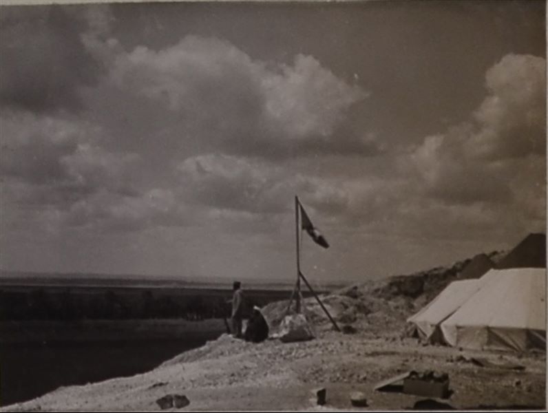 Accampamento della Missione Archeologica Italiana presso le grotte di Qau el-Kebir. Si riconosce il tuttofare, Benvenuto Savina, con il fucile in mano. Album fotografico, Scavi Schiaparelli.