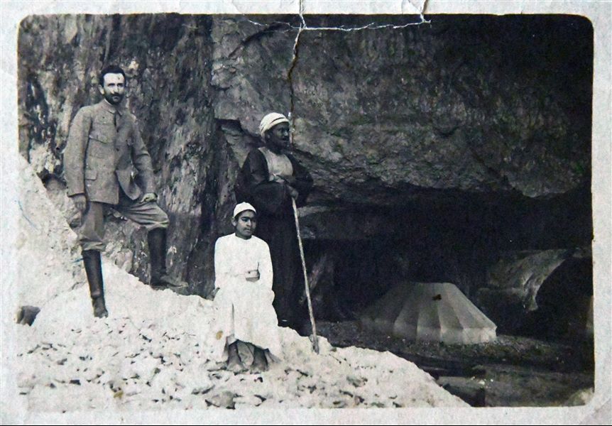 Francesco Ballerini fotografato insieme al rais Kalifa (anch’egli in piedi) e al giovane Buhus, davanti alla grotta che funse da accampamento durante gli scavi della Missione Archeologica Italiana nel 1905 e nel 1906 a Qau el-Kebir e Hammamiya. Archivio Angelo Sesana 