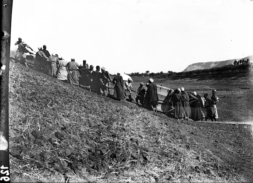 Trasporto delle casse contenenti antichità, durante il superamento di uno wadi. Il personaggio con l'ombrello potrebbe essere Schiaparelli. Scavi Schiaparelli.