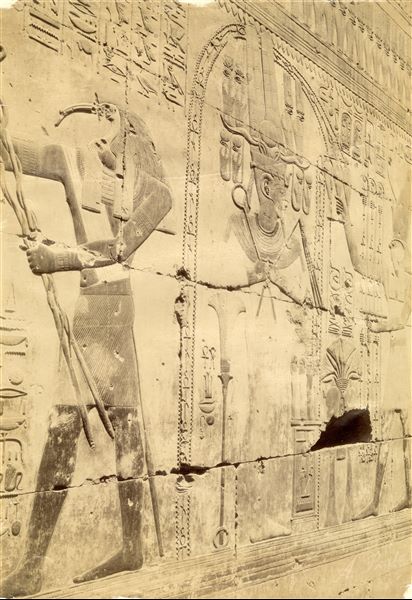 La fotografia mostra un particolare dei testi e delle immagini presso la cappella di Osiride nel tempio di Seti I ad Abido. Il dio Harsiesi (destra) purifica il faraone in vesti osiriache (al centro), mentre a sinistra il dio Thot compie un altro rituale. In basso a destra la firma dell’autore.