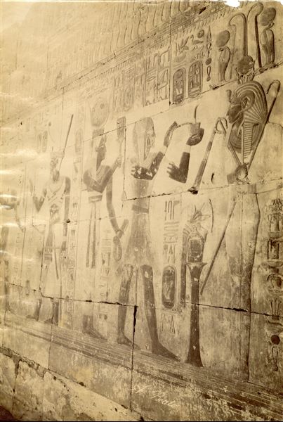 Lo scatto cattura un dettaglio delle scene a rilievo dalle pareti del tempio di Seti I ad Abido, nei pressi della cappella dedicata ad Osiride. La firma del fotografo è apposta in basso al centro.