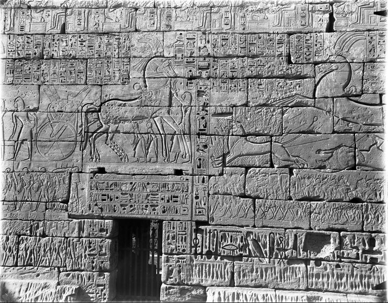 North wall, external facade from the temple of Ramesses III, near the access to the second court. In the main scene, Ramesses III is shown hunting lions.